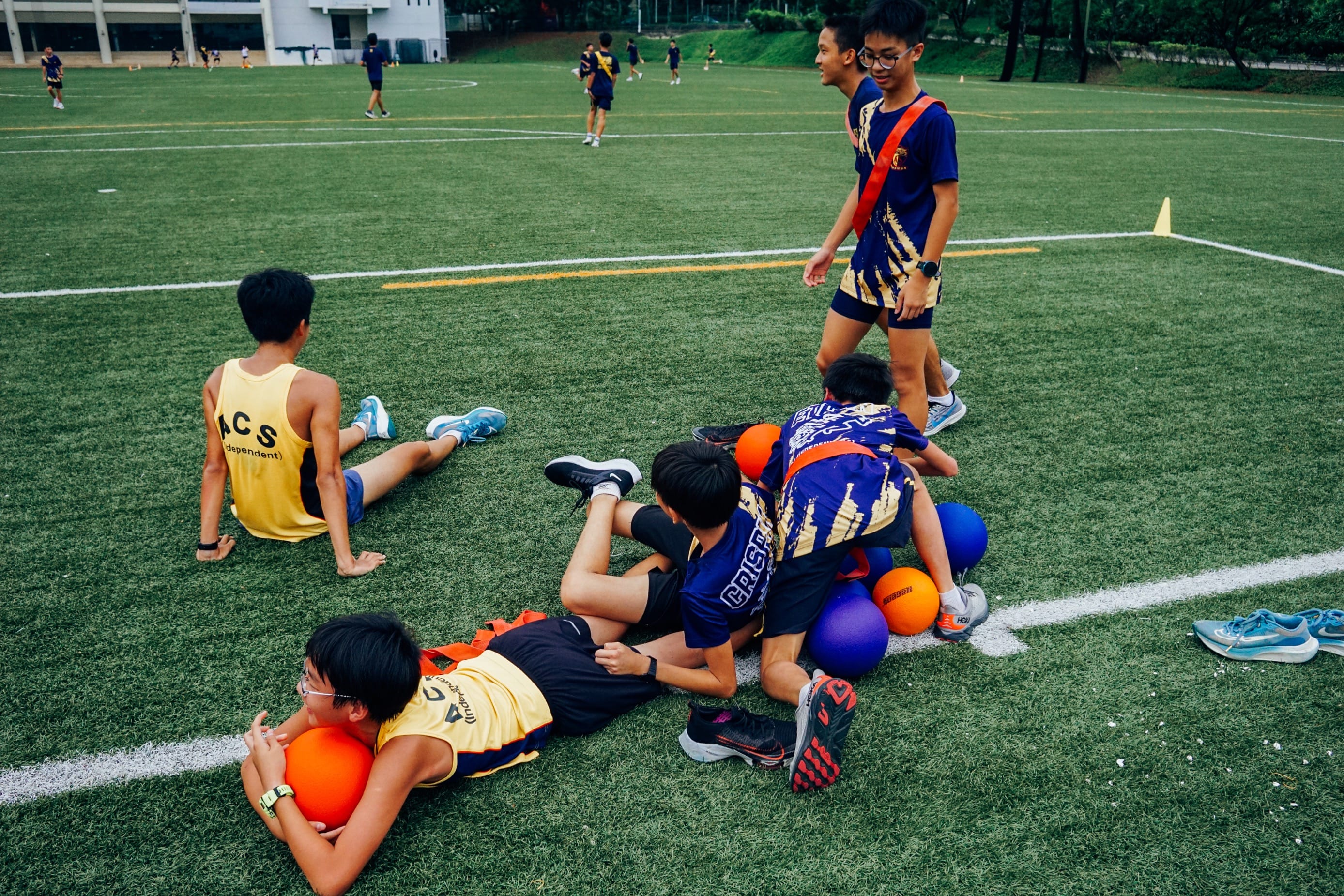A group of students laying and sitting on a field